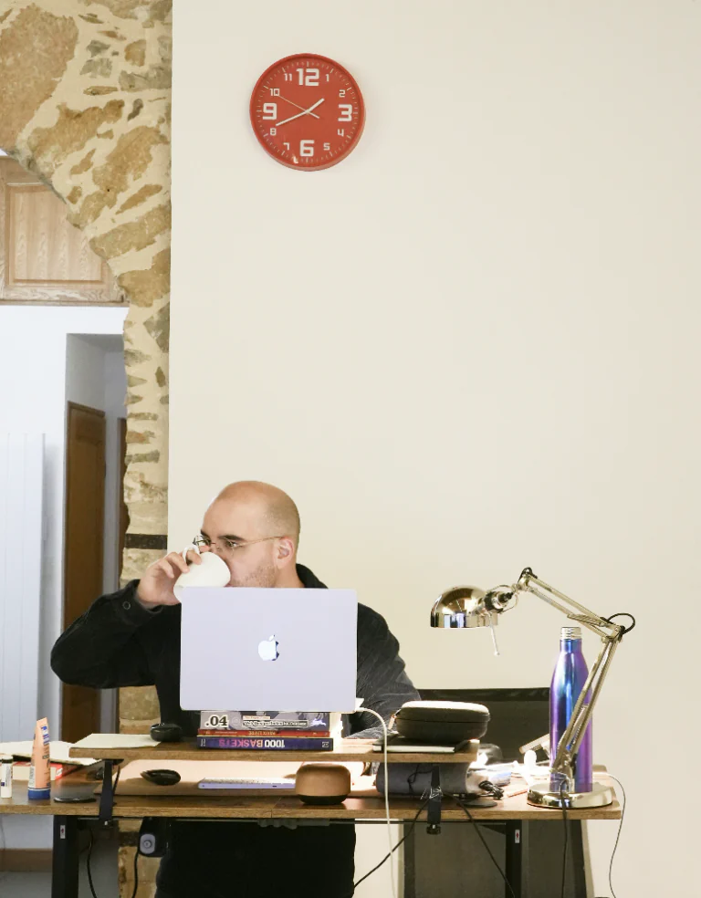 Un coworker travaille derrière son ordinateur, près de l’arche en pierre
